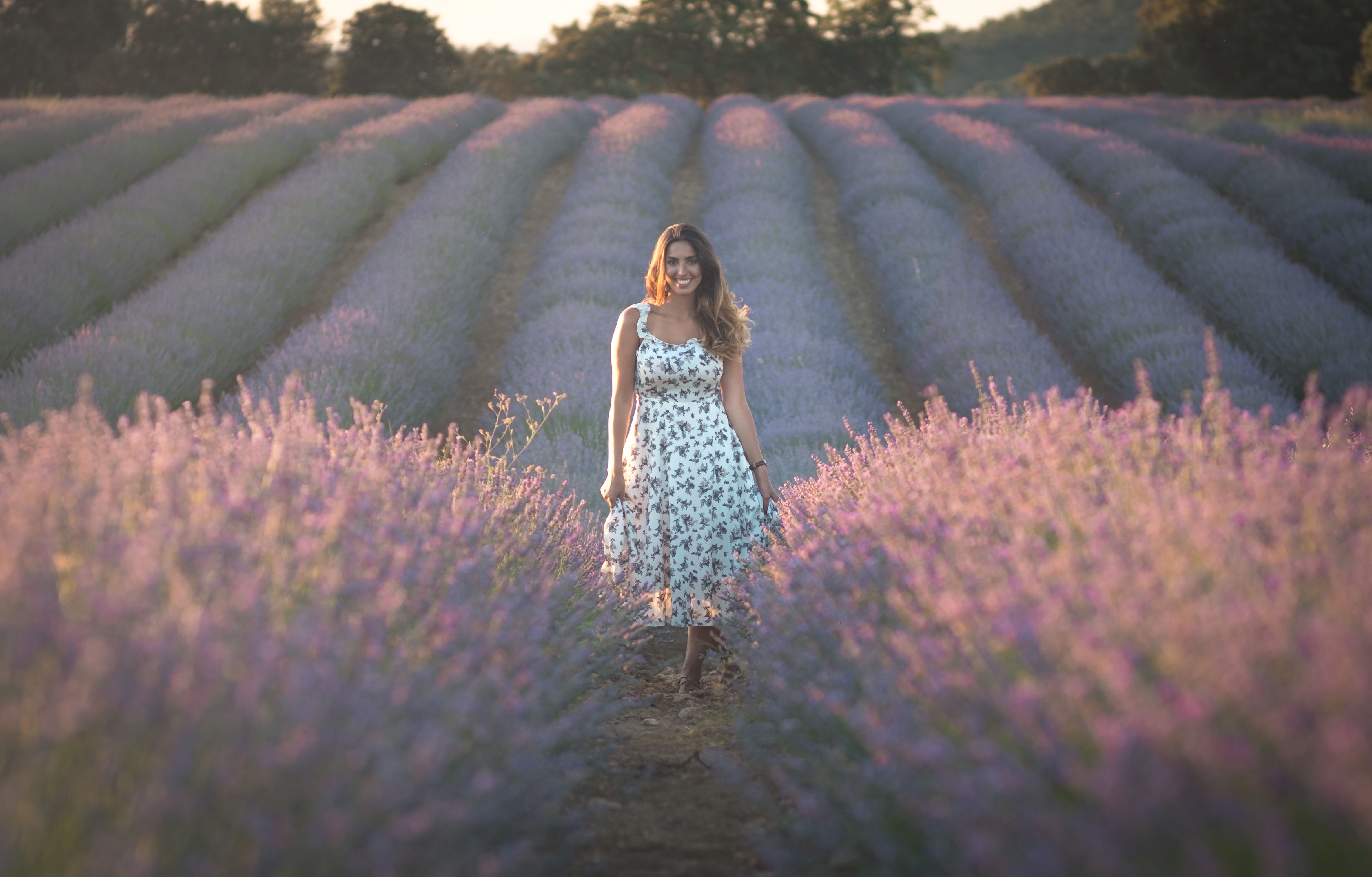 A Smiling Woman in White Floral Dress Standing on a Flower Field · Free ...