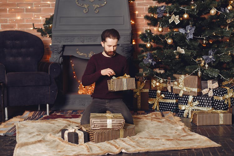 Man Unpacking Presents Near Fireplace