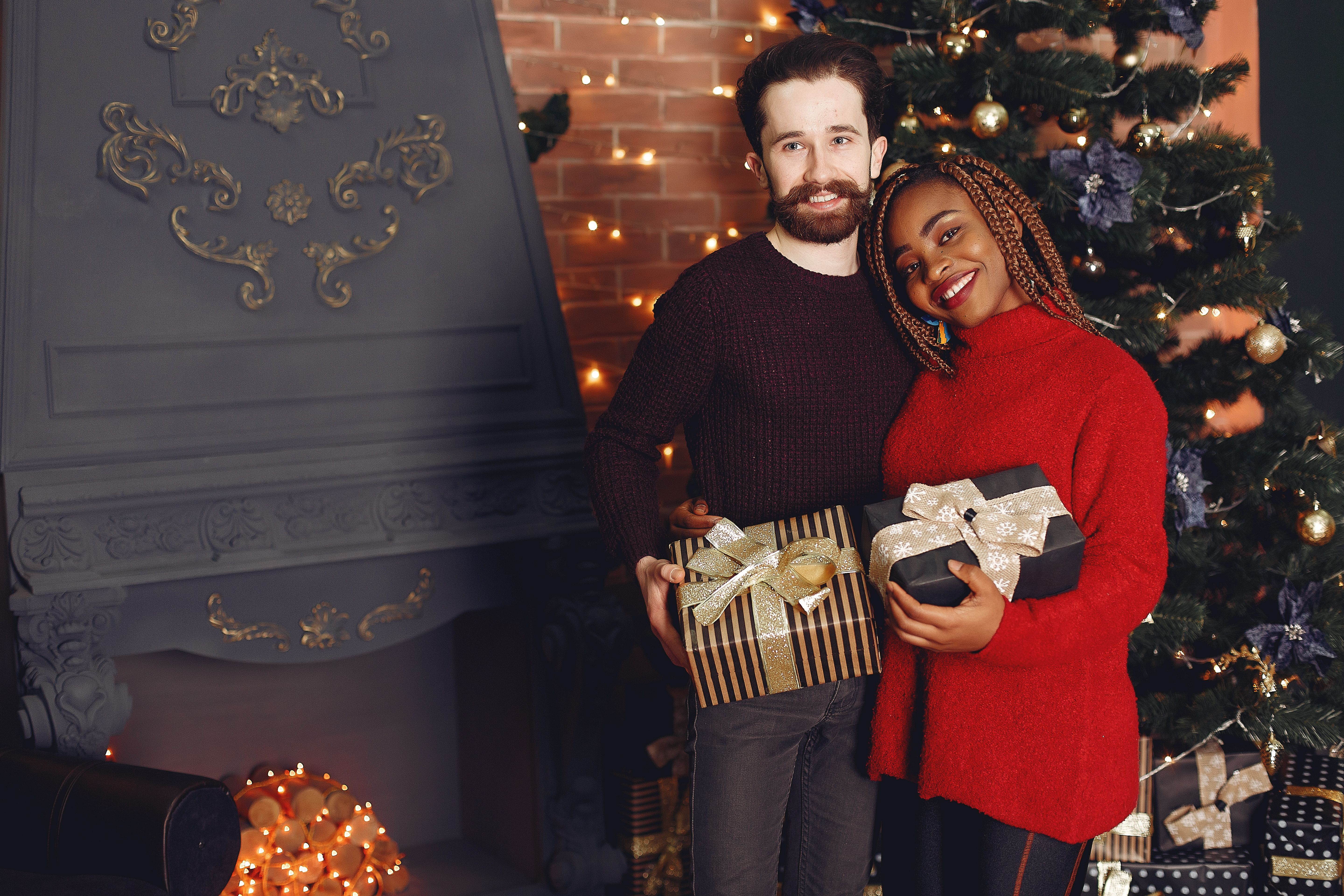 A joyful couple exchanging gifts by the Christmas tree, celebrating the festive winter holiday.