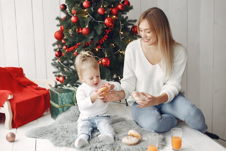 Mother And Child Eating Donuts By Christmas Tree 