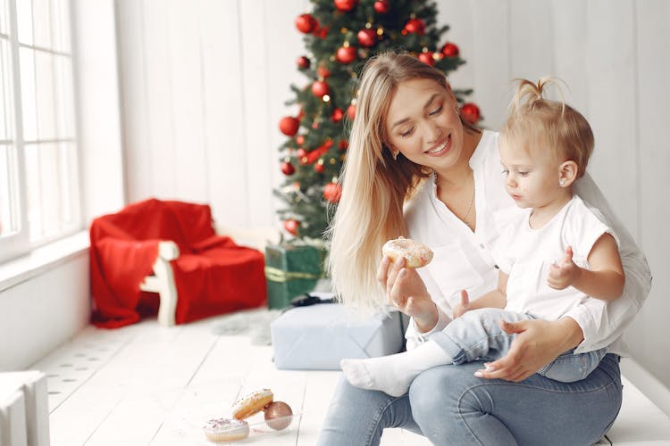 Woman Holding A Baby While Eating A Donut