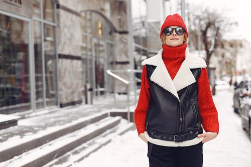Free Fashionable woman in red and black winter attire on a snowy city sidewalk. Stock Photo