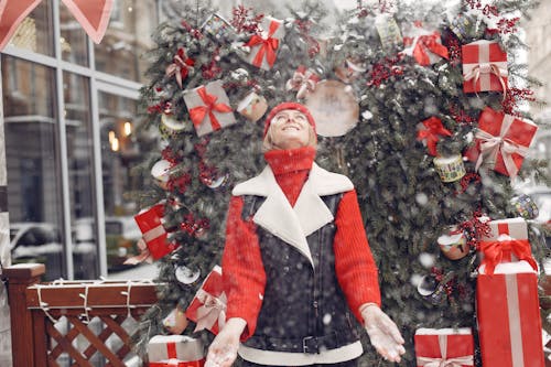 Woman in Red Knitted Sweater Standing Near Christmas Gifts