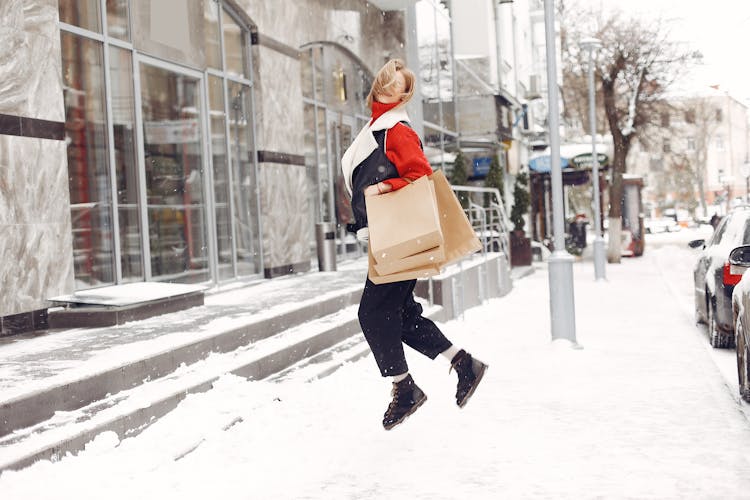 A Happy Woman Holding Shopping Bags Jumping 