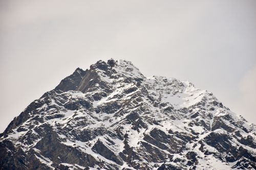 Free Majestic snow-covered mountain peak with a white sky backdrop, offering a serene winter scene. Stock Photo