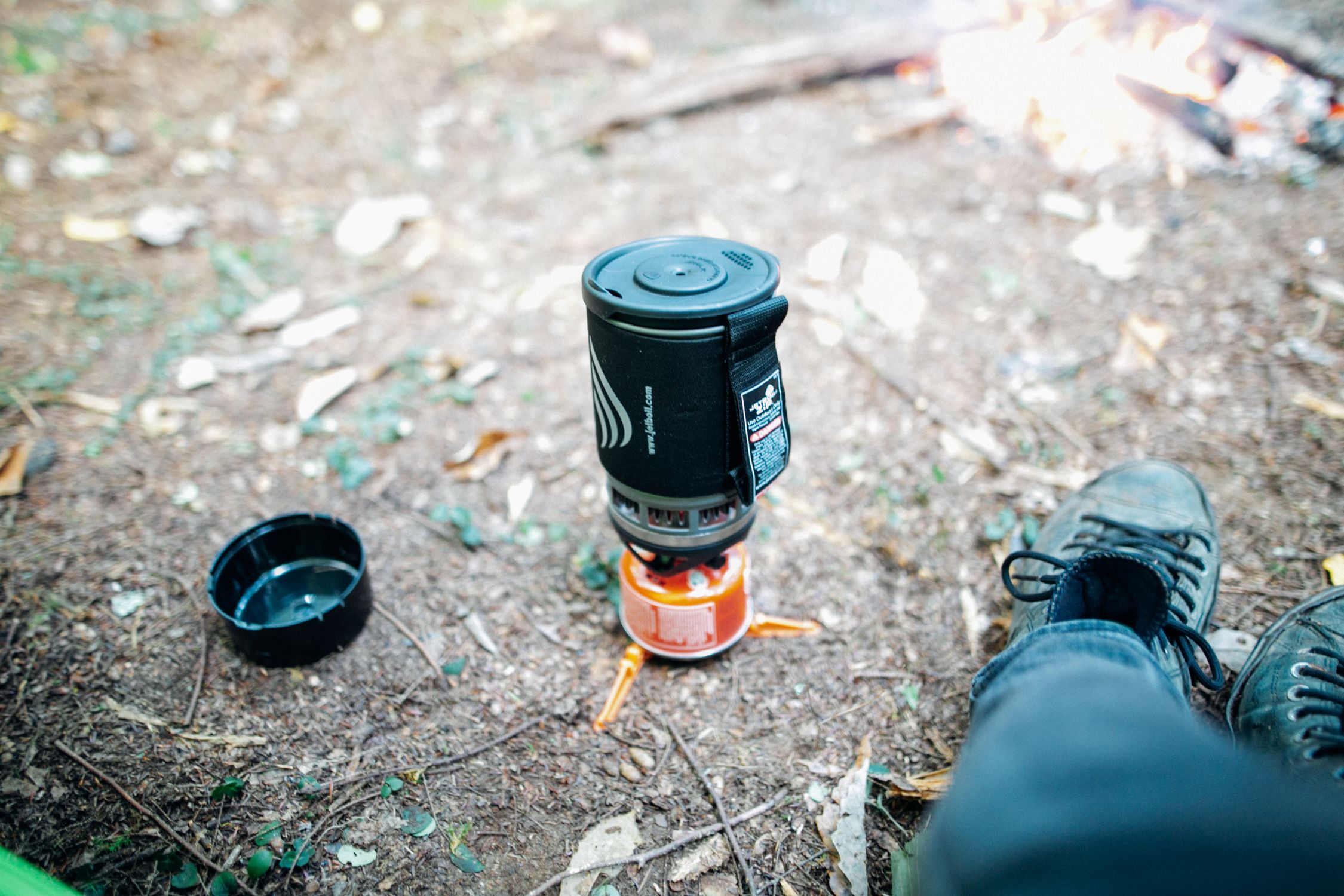 Outdoor camping scene with portable stove and campfire in autumn forest