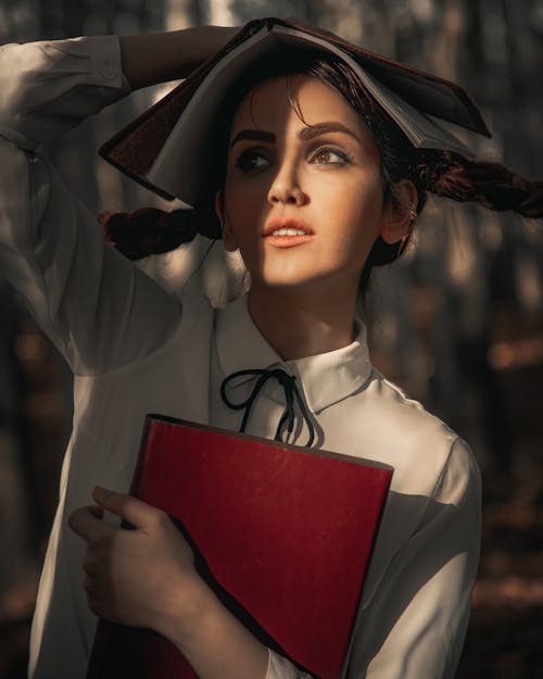 Woman in White Long Sleeve Shirt Holding Red Book