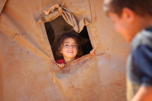 Smiling little ethnic girl looking out of window in tent