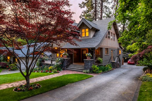 Beautiful suburban house with a red maple tree at twilight, showcasing elegant landscaping.