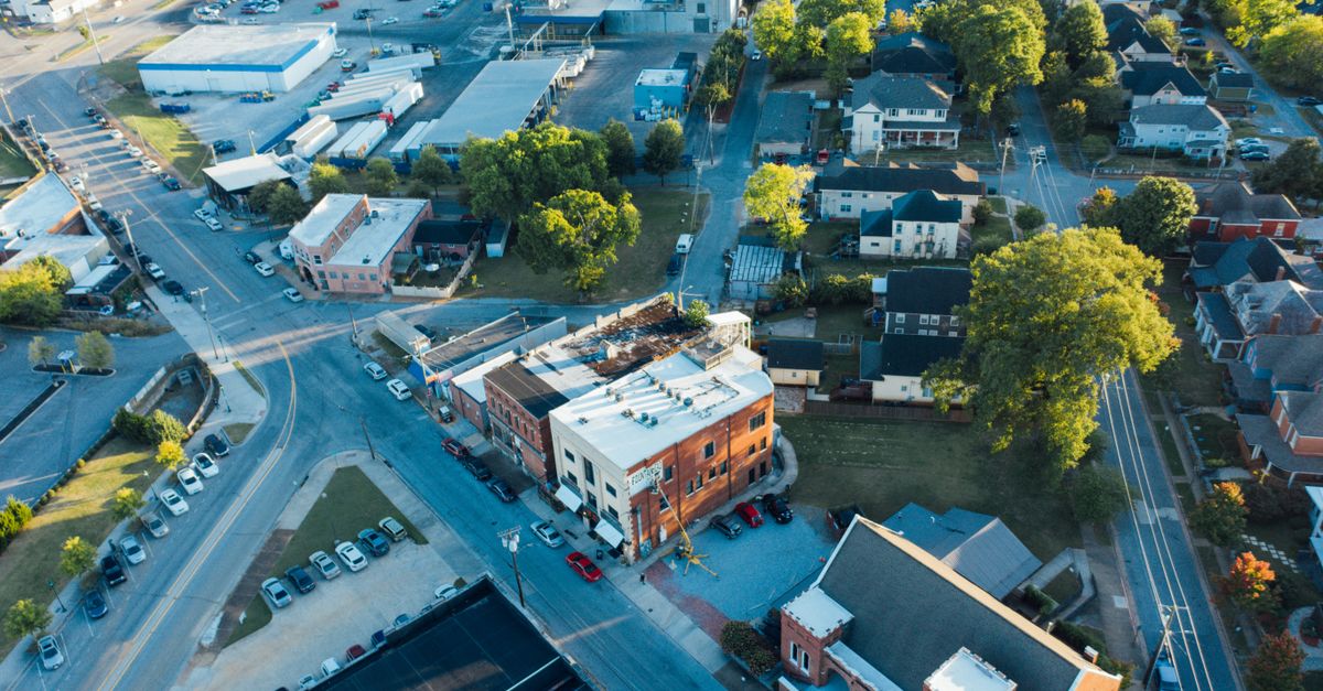 Drone view of typical small buildings located near asphalt roads in suburban district on sunny day