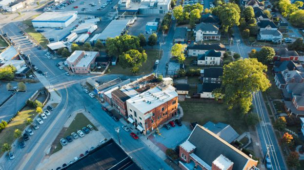 Drone view of typical small buildings located near asphalt roads in suburban district on sunny day