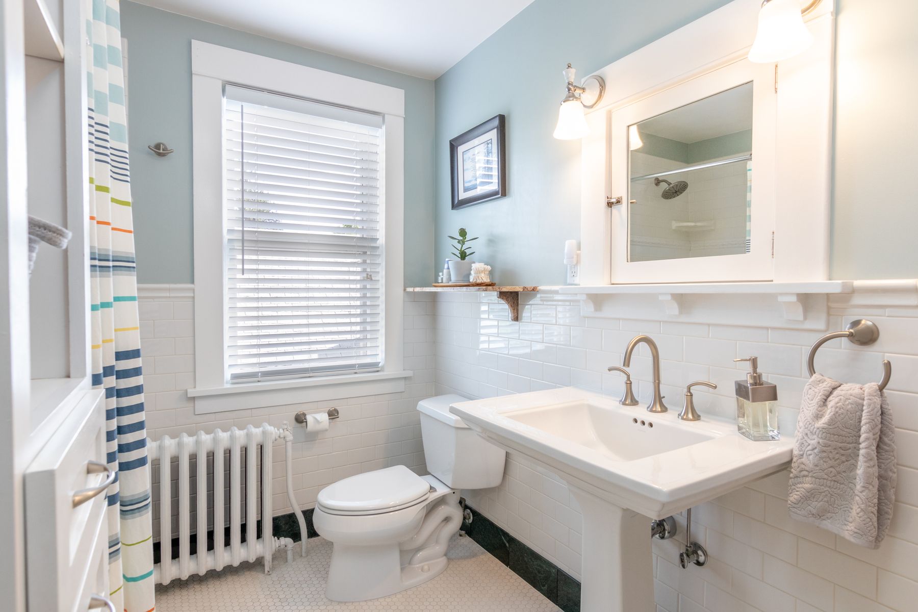 Bright bathroom with white tile, pedestal sink and natural light