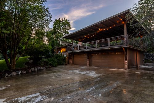 Spacious home exterior lit by string lights at twilight, framed by landscaped greenery