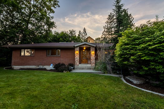 A cozy brick house surrounded by greenery, captured during twilight. Perfect for real estate promos.