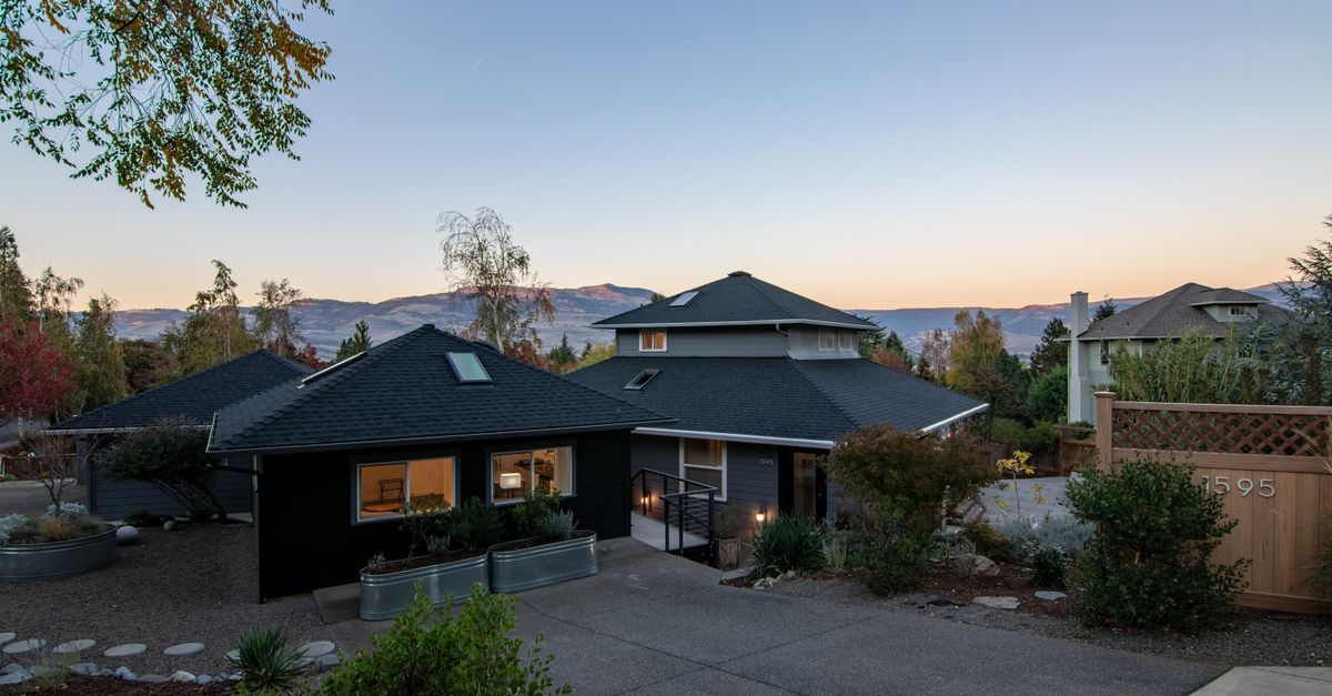 Elegant suburban house with spacious driveway and stunning mountain views at sunset.