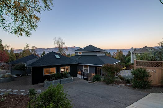 Elegant suburban house with spacious driveway and stunning mountain views at sunset.
