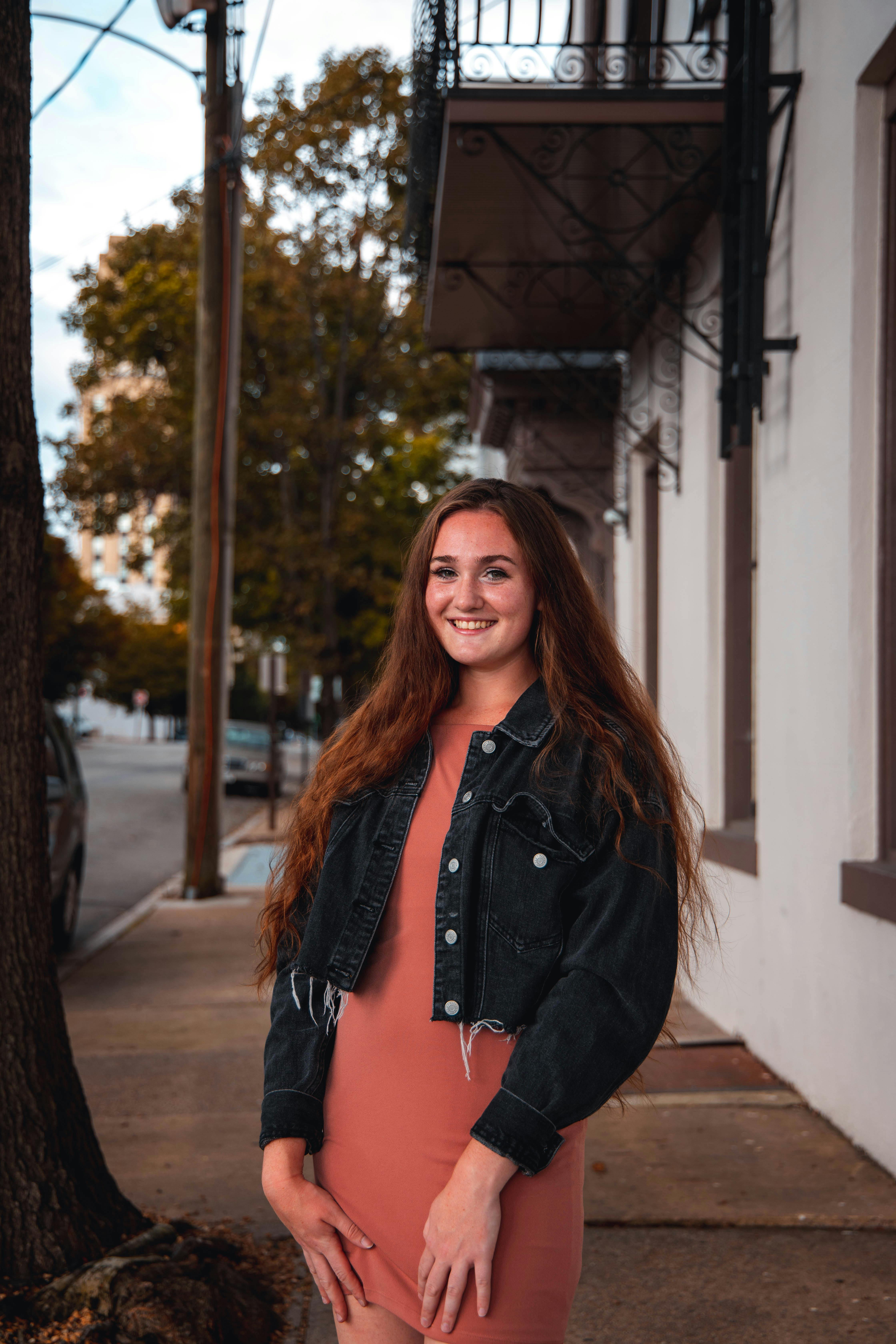 Young woman smiling outdoors in urban street with modern residential facades.
