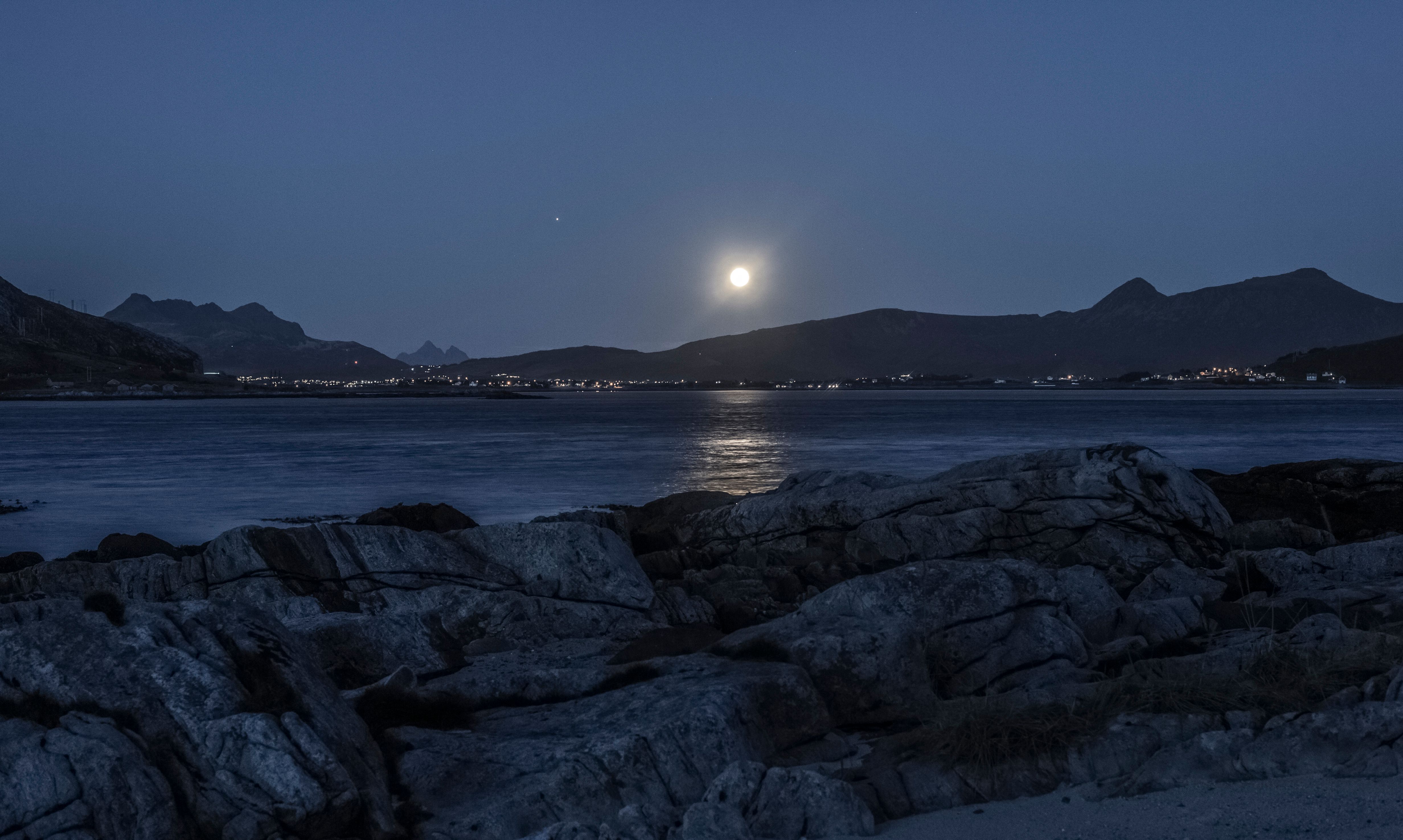 夜晚，阳光照亮了万里无云的天空下、波纹海洋附近的山脊景观