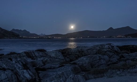 夜晚，阳光照亮了万里无云的天空下、波纹海洋附近的山脊景观