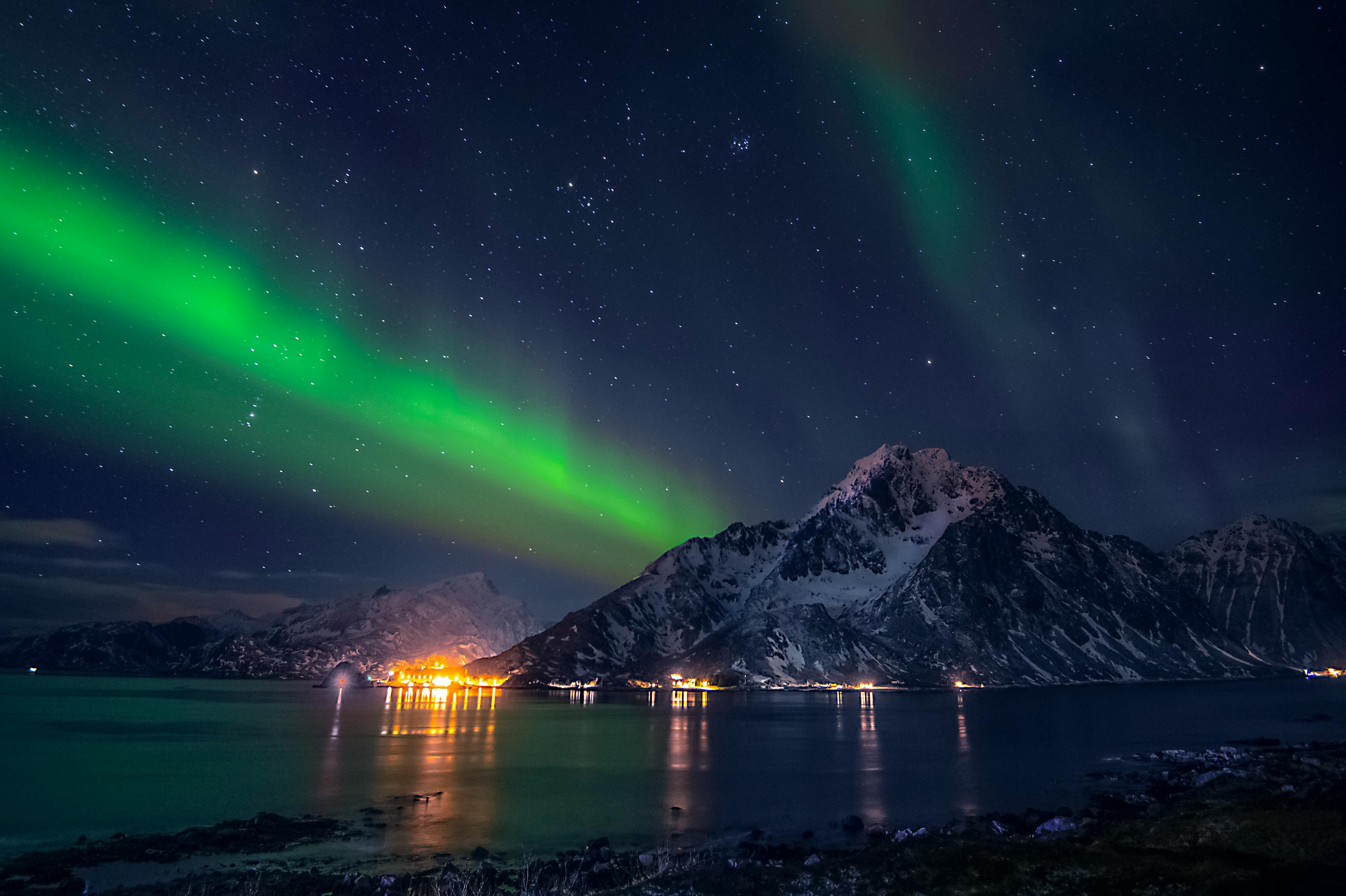 Colorful northern lights in sky above mounts and sea · Free Stock Photo