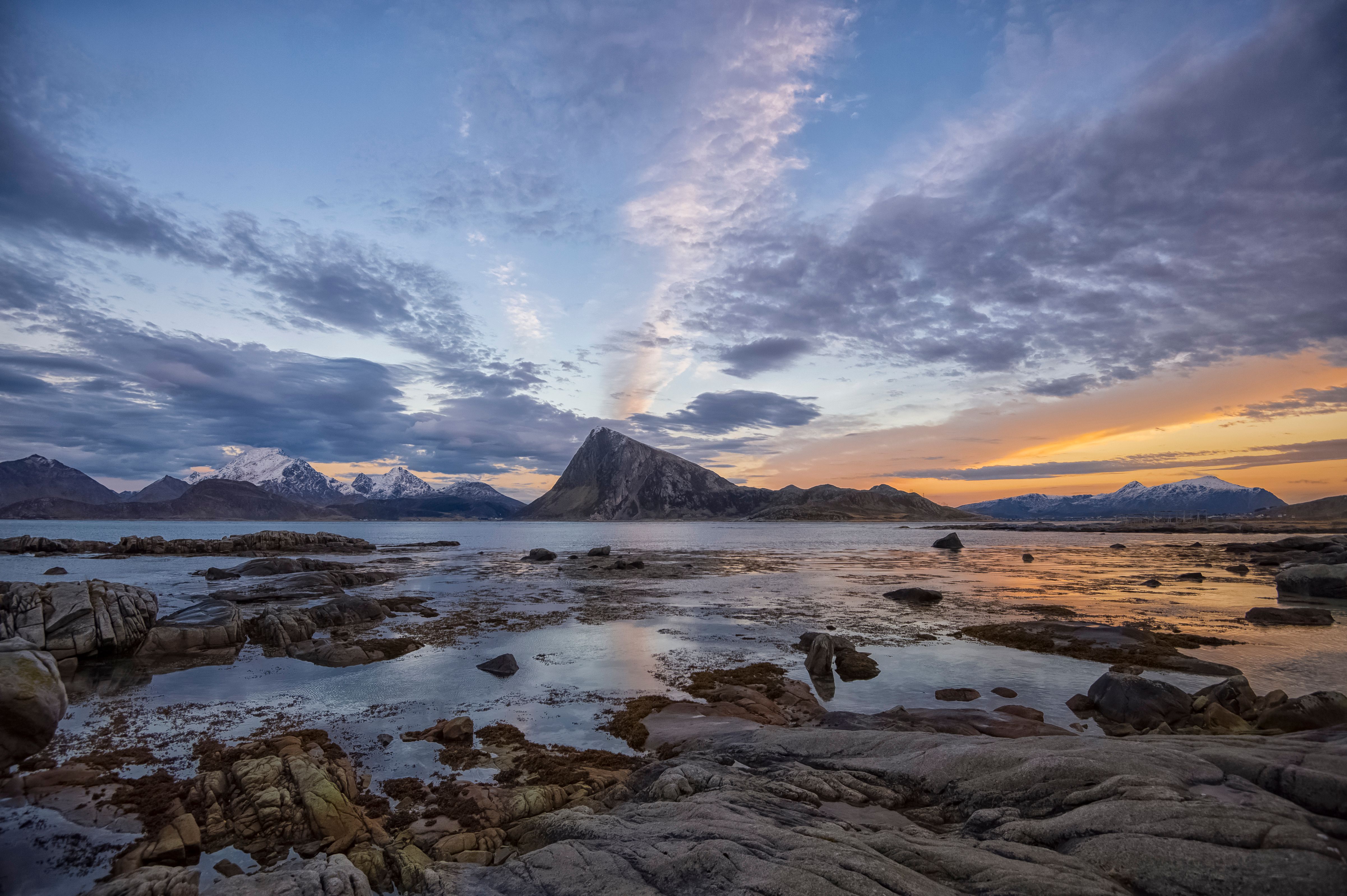 Sunset sky over ocean surrounded by snowy mountains · Free Stock Photo