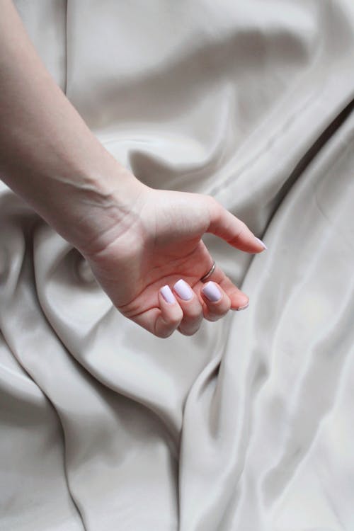 A Person Hand Hanging Over a Silk Fabric
