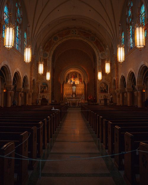 Free Stunning view of a Gothic church interior featuring an ornate altar with stained glass windows. Stock Photo
