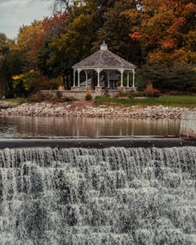 秋天的公园风景如画，宁静的瀑布旁有一座迷人的凉亭