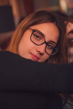 Attractive female with light makeup in eyeglasses and casual outfit smiling while looking at camera