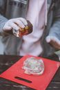 Crop unrecognizable male chef pouring seasonings on beef steak for picnic in backyard
