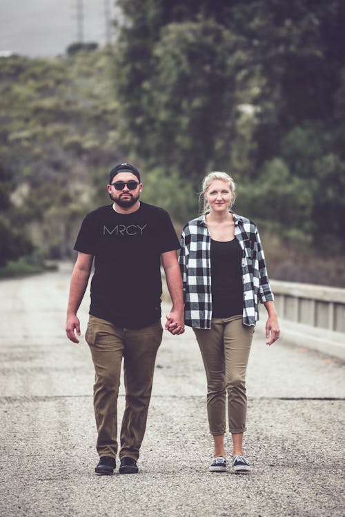 Free Shallow Focus of a Romantic Couple Walking on the Road while Holding Hands Together Stock Photo
