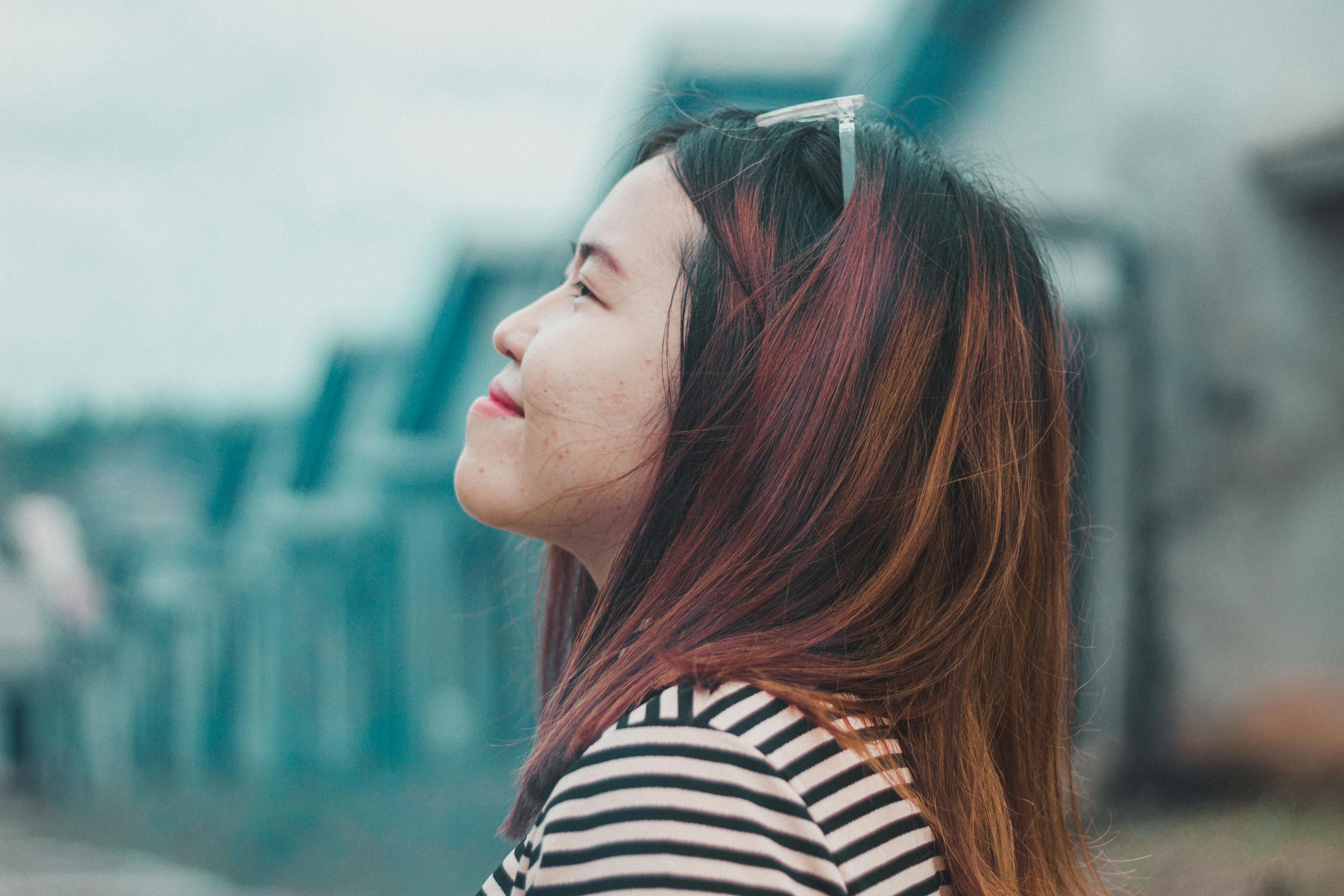 A smiling woman in a striped shirt enjoys the outdoors, captured in a serene moment.