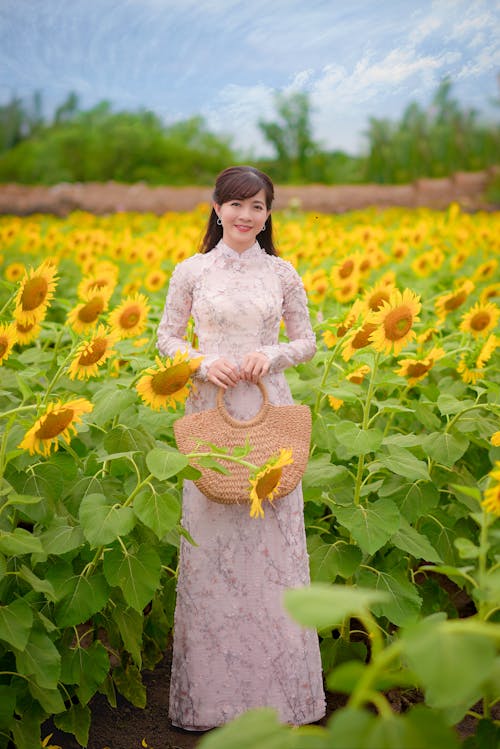 Woman in Floral Dress Standing on Yellow Flower Field