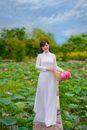 Woman in White Long Sleeve Dress Holding Pink Flower