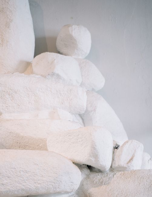 A minimalist stack of textured white rocks forming an abstract sculpture indoors.