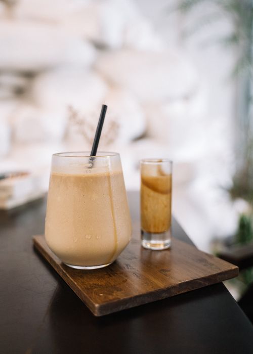 Free Close-up view of a refreshing iced coffee with a straw, served on a wooden tray. Stock Photo