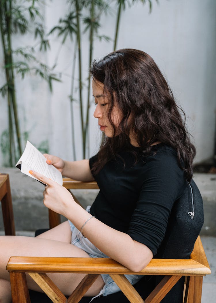 A Girl In A Black Top Reading A Book