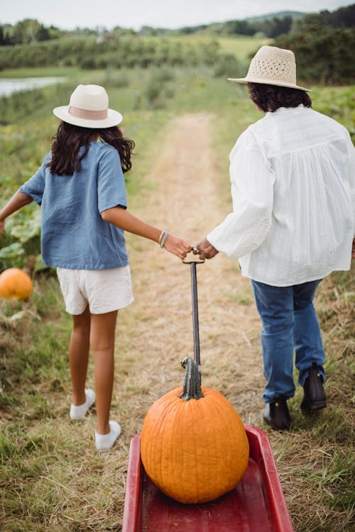Woman with daughter leading cart with pumpkin