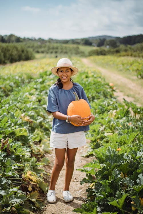 Happy young girl with pumpkin in field