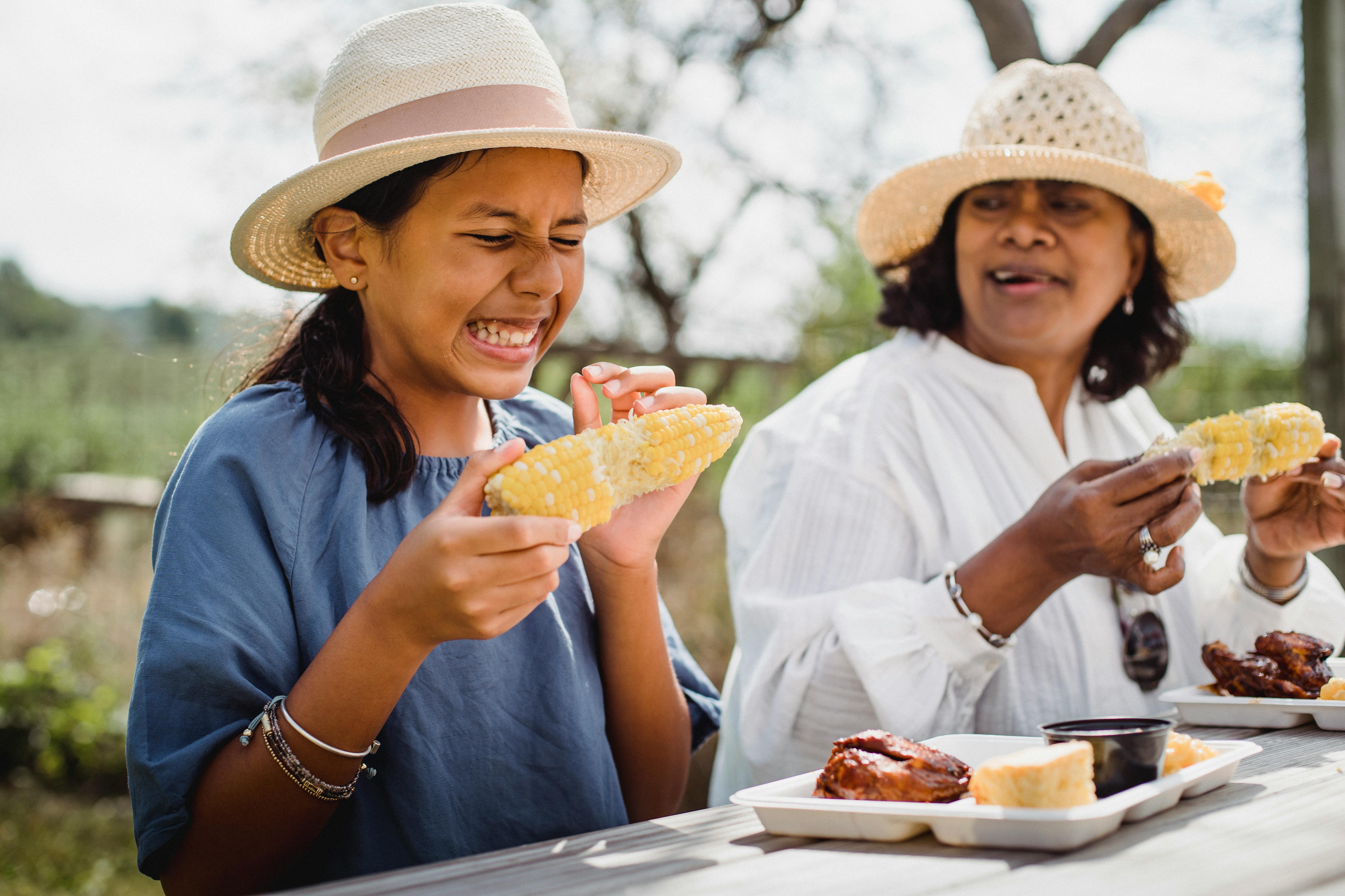 ethnic funny girl eating with mother in backyard