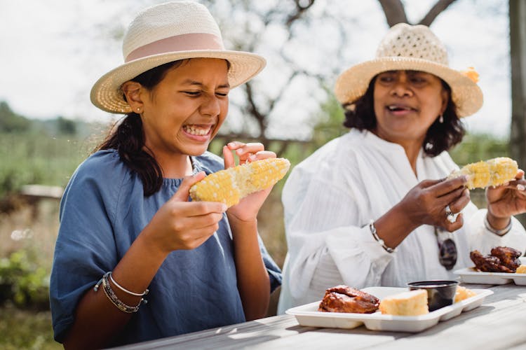 Ethnic Funny Girl Eating With Mother In Backyard