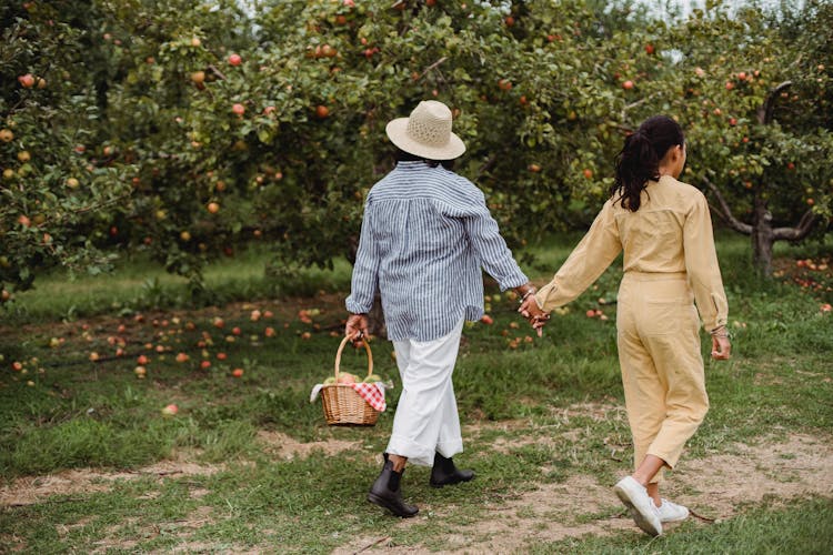 Ethnic Mom And Daughter Walking Together In Garden