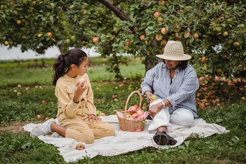 Free Ethnic girl enjoying rest with mother in orchard Stock Photo