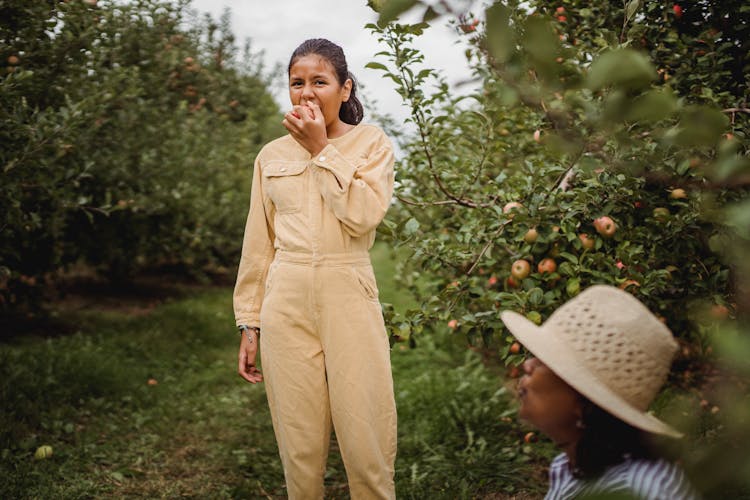 Ethnic Girl Biting Apple In Garden