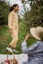 Side view of disappointed Hispanic teen girl standing on grass near apple trees during picnic with mother
