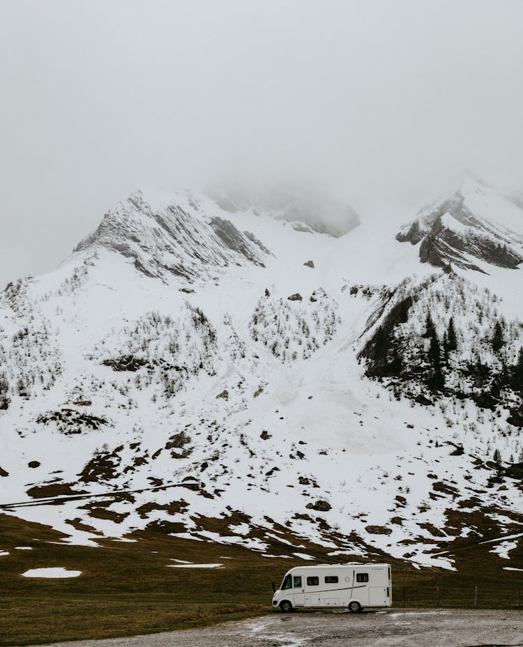 Camper Van On Road Near Snowy Mountains