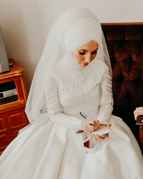Bride In Wedding Dress Writing On Sole Of A High Heel Shoe 