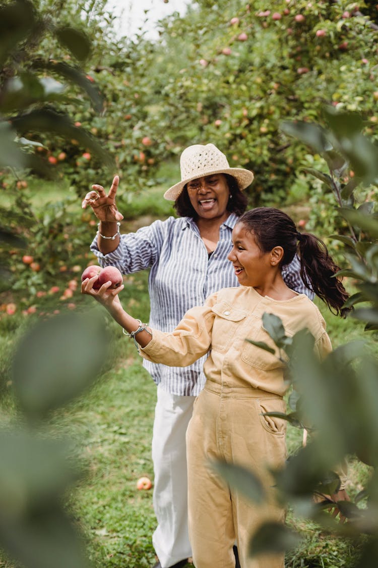 Happy Hispanic Woman And Young Girl With Apples