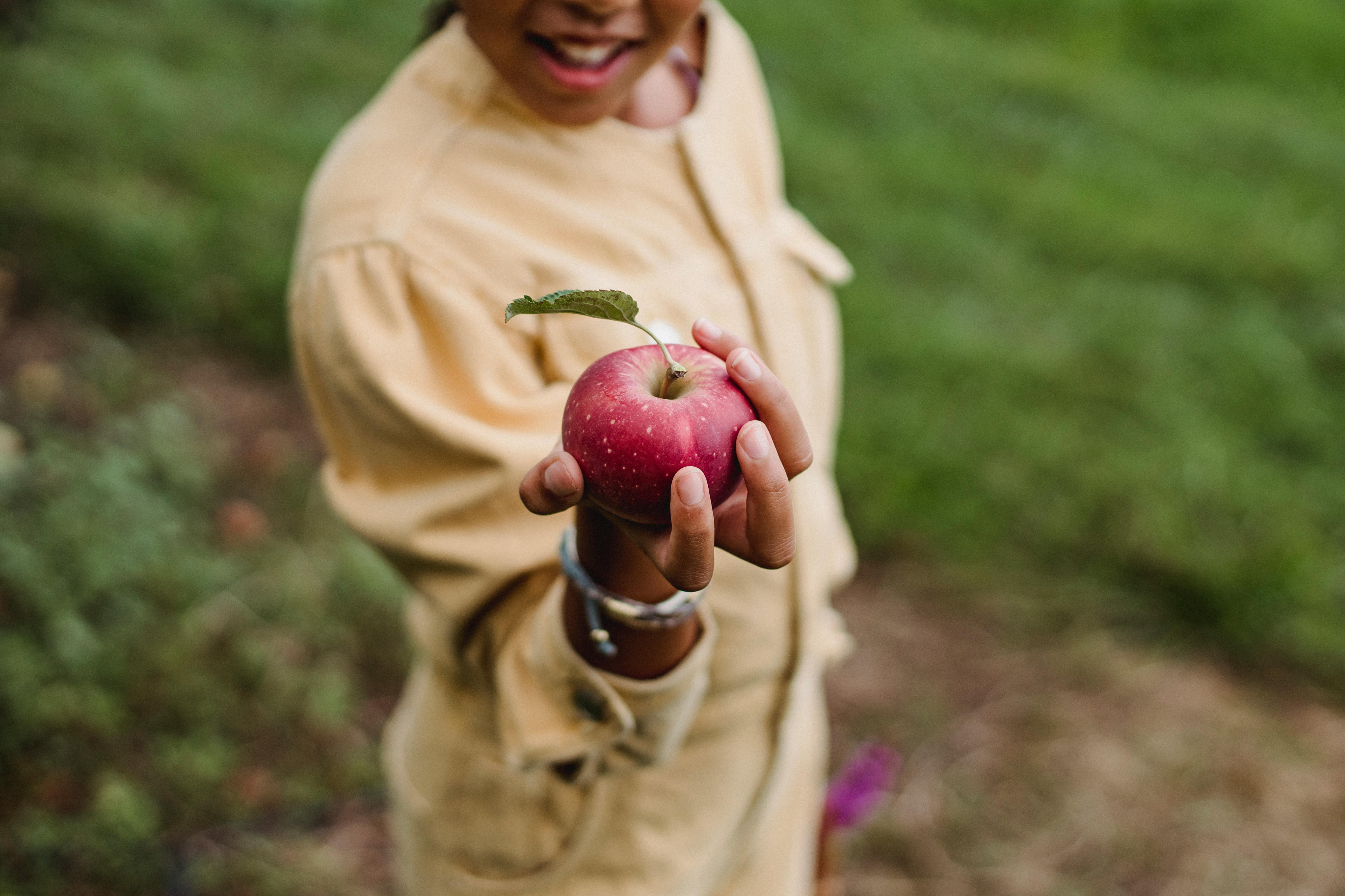 crop teen girl showing ripe apple