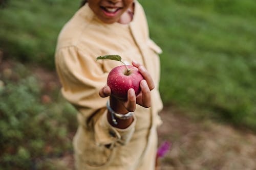 Crop teen girl showing ripe apple
